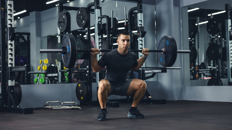 A young person doing a squat with a barbell.