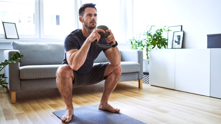 A person doing a kettlebell goblet squat at home.