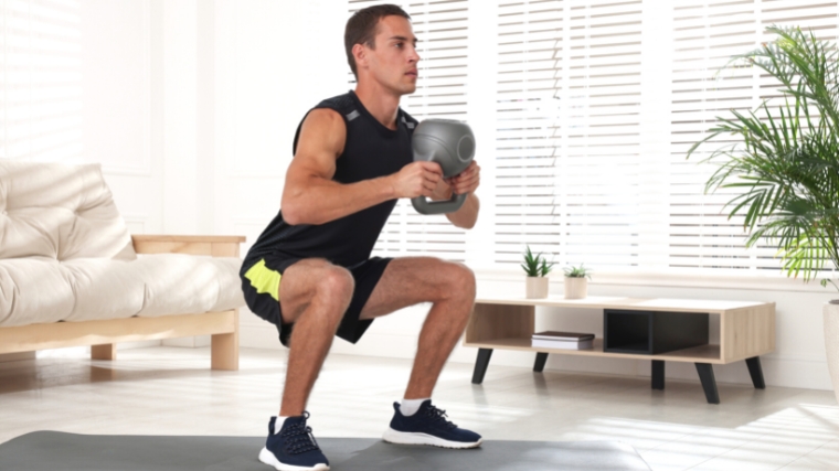 A person doing a kettlebell goblet squat in the standard squat position.
