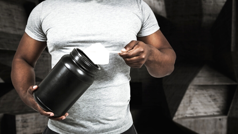 A person scooping powder from supplement container.