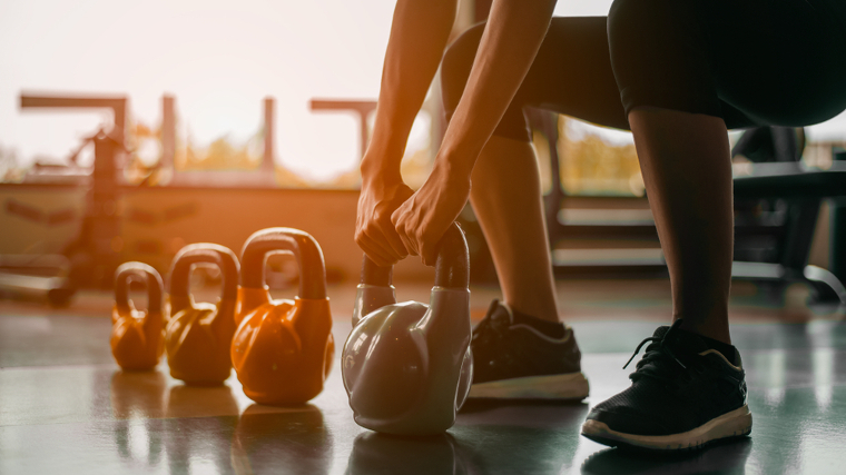 A person grabbing a kettlebell off the ground.