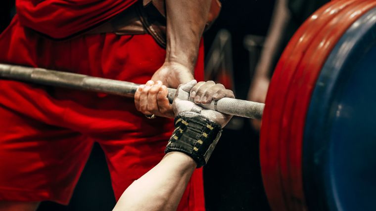 A close-up photo of a hand on a barbell.