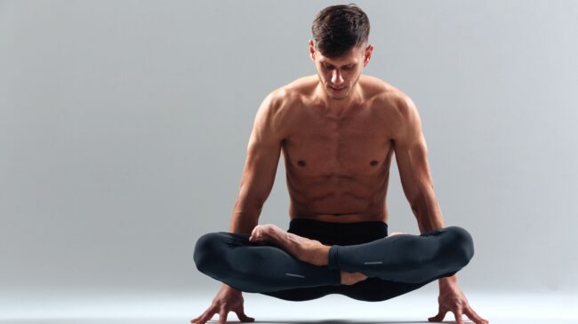 A shirtless muscular person doing yoga.