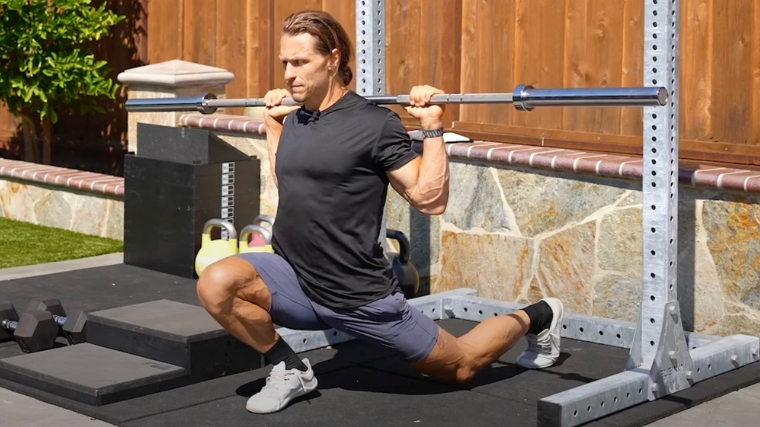 A person doing an ATG split squat with a barbell.