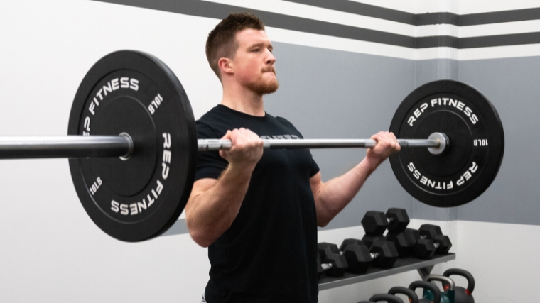 A person in a black shirt doing barbell biceps curls.