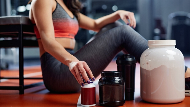  A person with a line of supplement containers on the gym floor.