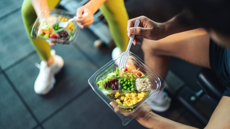 Two people eating healthy food at the gym.