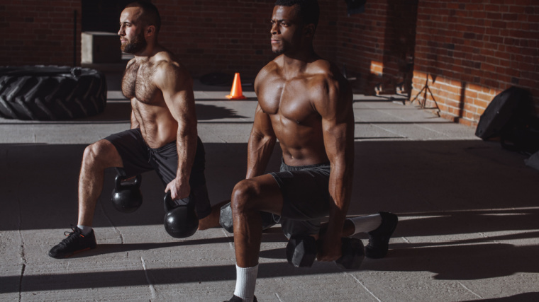 Two shirtless athletes perform dumbbell lunges.