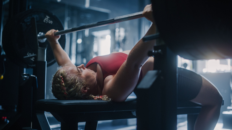 Woman sets up to perform flat bench press with back arch