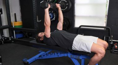 A person doing the dumbbell bench press on a flat weight bench.