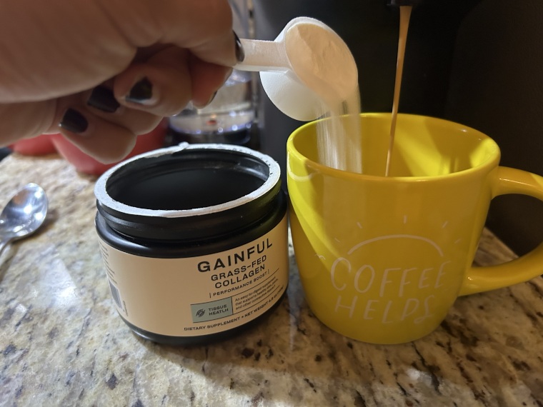 Pouring a scoop of Gainful Collagen into a cup of coffee.