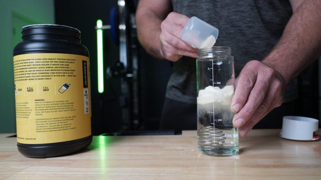 A person mixing Jacked Factory Authentic ISO protein powder in a clear glass