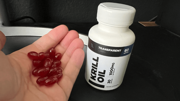 A hand filled with Transparent Lab Krill Oil capsules. 