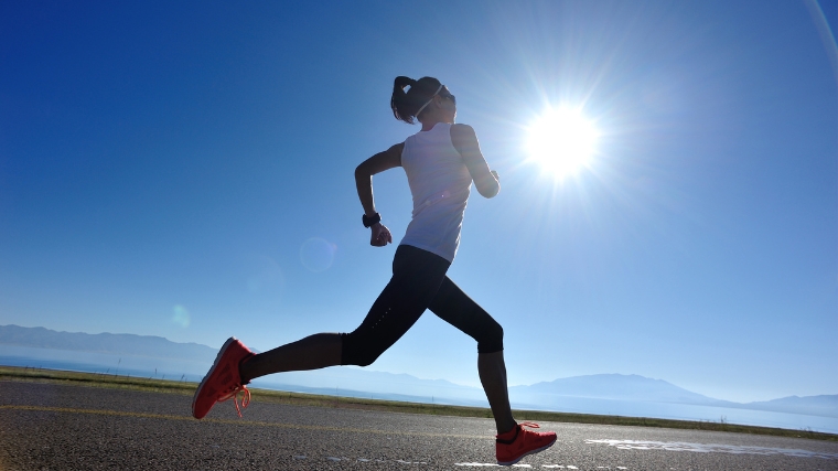 A person running on pavement under the hot sun.