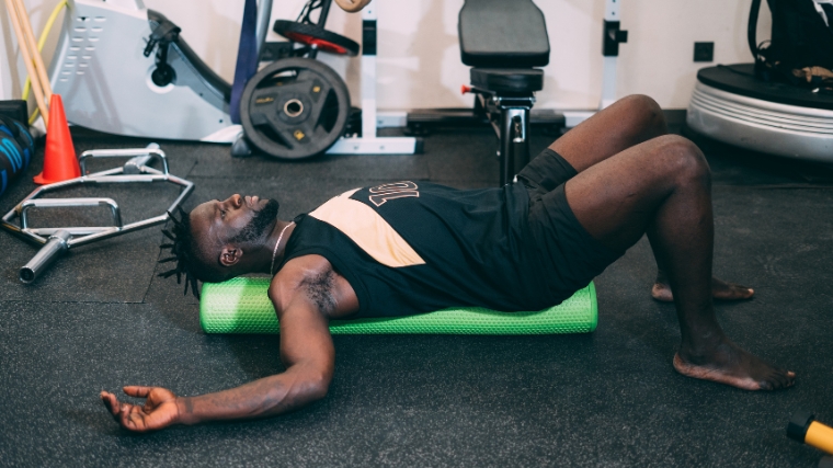  An athlete using a foam roller to relieve sore muscles.