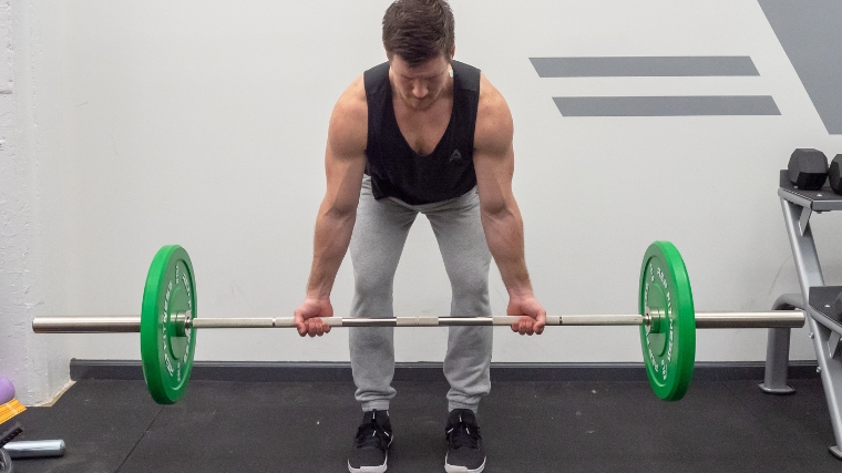 A person doing the first step of the Reverse-Grip Bent-Over Row.