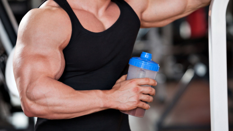 Bodybuilder in tank top drinking protein shake