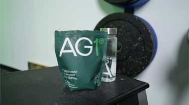 A bag of AG1 Greens Powder on a bench in a gym.