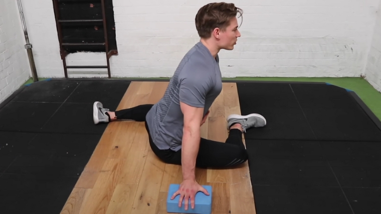 A muscular person setting up their chest for the 90/90 stretch.