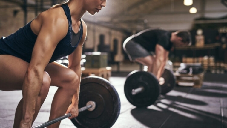 Two people doing deadlifts in the gym.