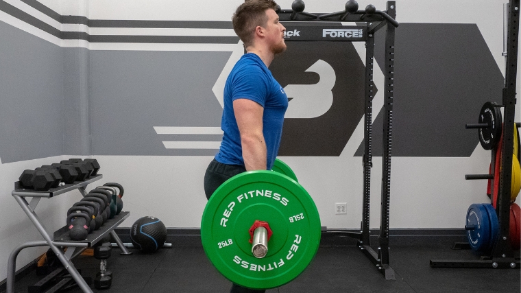Side view of a coach deadlifting in the Barbend gym.
