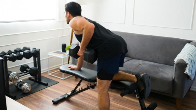 A person performing dumbbell rows at home.