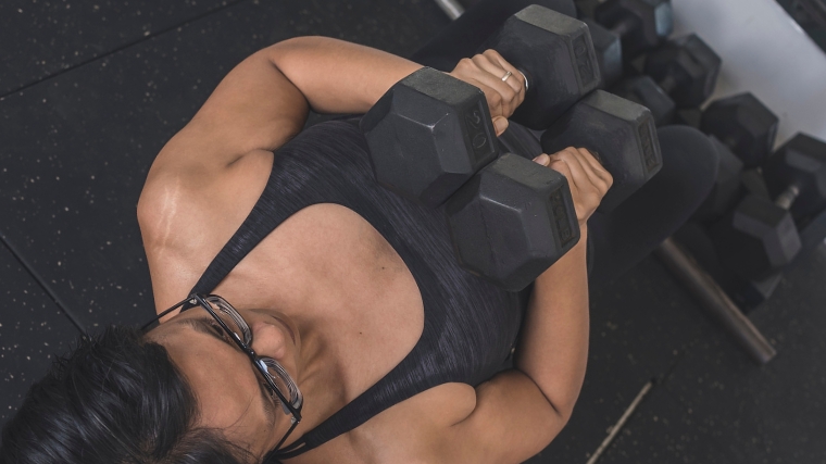 A person doing the hex press, with the hex dumbbells lowered together and touching the chest.