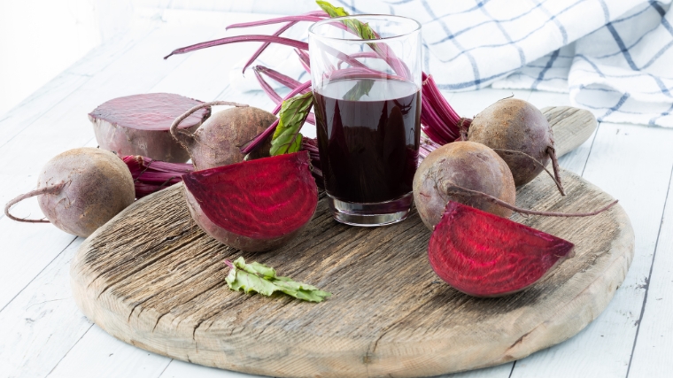 Beets around a glass of beetroot juice.