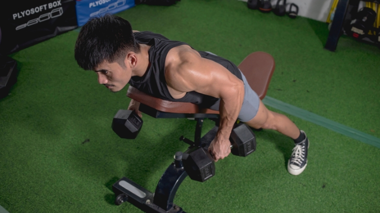 A muscular person doing chest-supported dumbbells rows.