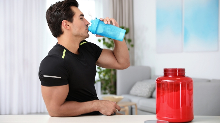 A person drinking pre-workout or creatine in a shaker bottle.