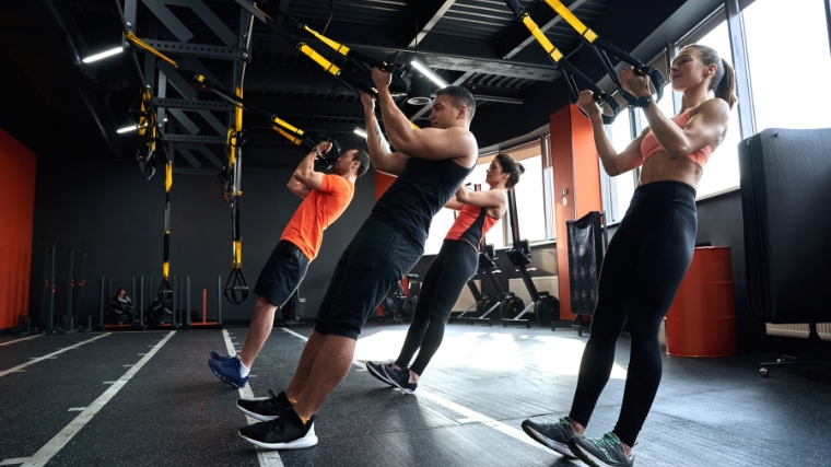 A group of people doing TRX suspension curls.