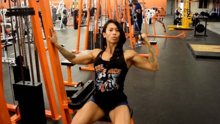 A muscular person doing a single arm lat pulldown.
