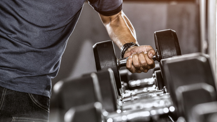 Man grabs dumbbell off of rack for hex press 