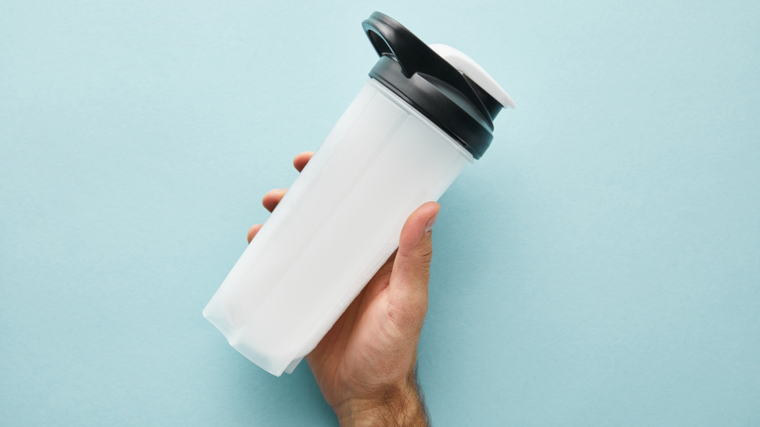 A person holding a protein shaker bottle.