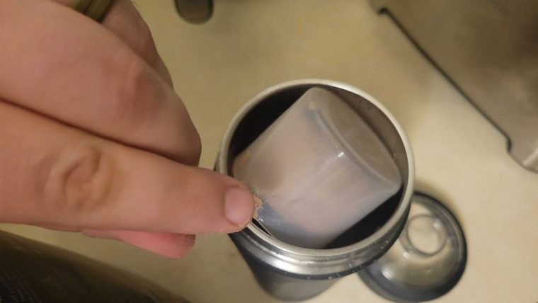 Someone dumping a scoop of Sports Research Whey Protein Isolate into a shaker bottle.