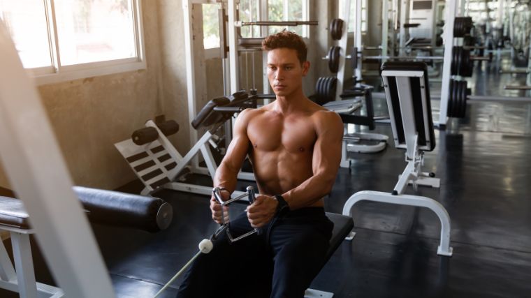 Shirtless man performing a seated cable row.