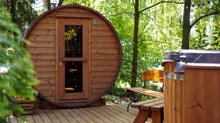 A barrel sauna on a wooden deck in the forrest