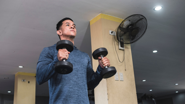 An athlete performs hammer curls in the gym.