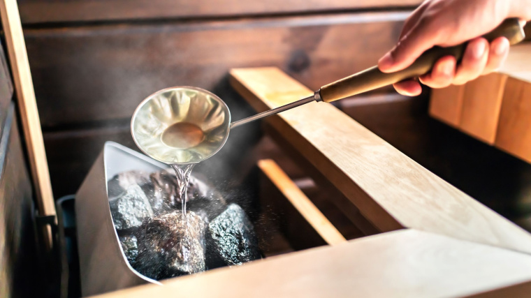 water being poured over sauna rocks to create steam