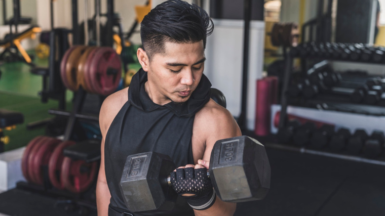 An athlete performs a heavy biceps curl in the gym.