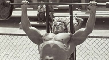 An old photo of Arnold Schwarzenegger bench pressing.