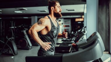 A bodybuilder reaping the benefits of treadmills by exercising on one.