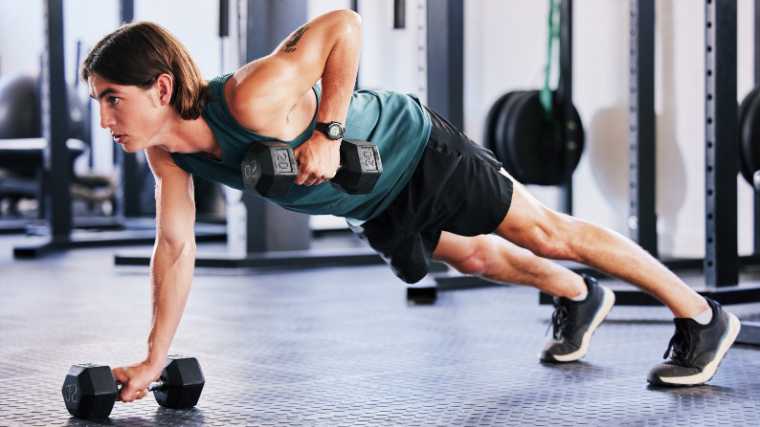 A gymgoer using two dumbbells to do renegade rows.