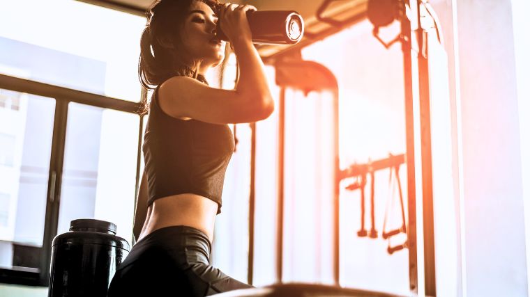 A gymgoer about to drink from a shaker bottle.