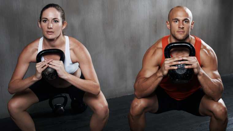 Two people doing goblet squats with kettlebells.