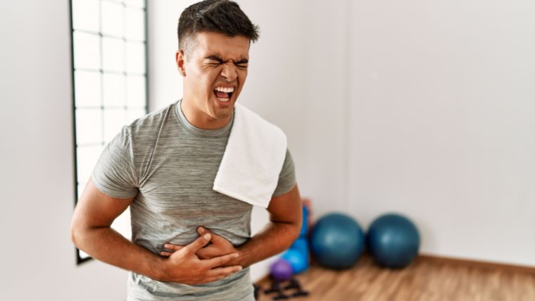 A person clutching their stomach in the gym.