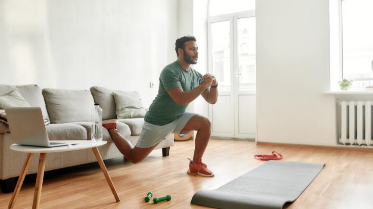 A person stretching in their living room, doing a Bulgarian squat.