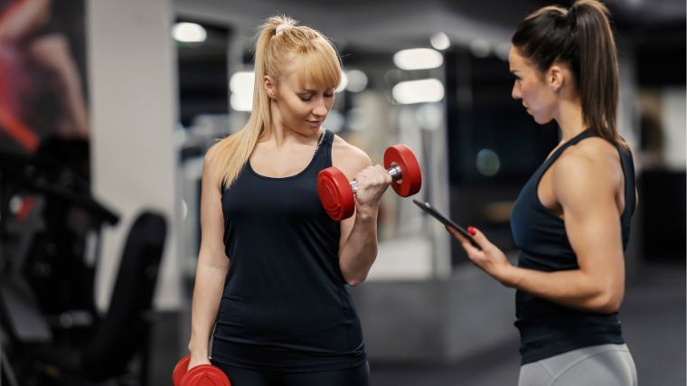 A beginner being coached on working out with dumbbells.