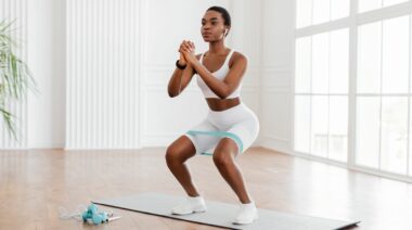 A person doing air squats with resistance band at home.