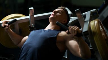 A bodybuilder using a chest press machine in the gym.